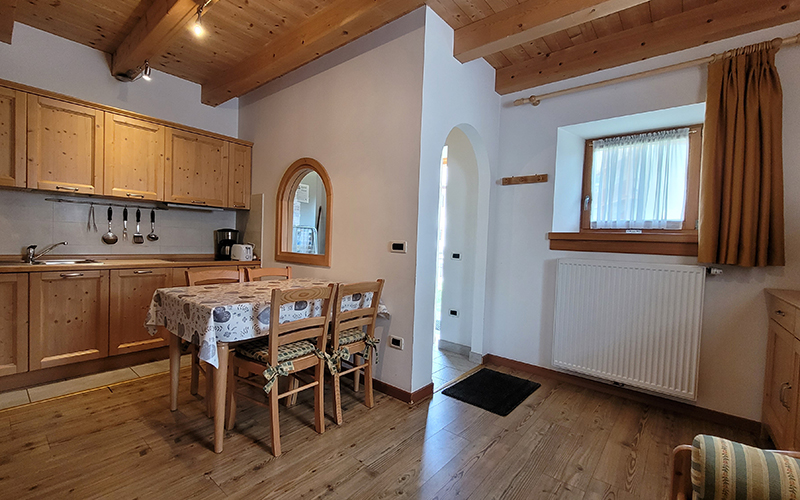 Küche und Essbereich eines Chalet Royal Apartments in Arabba, mit hellen Holzmöbeln und Sichtbalken.