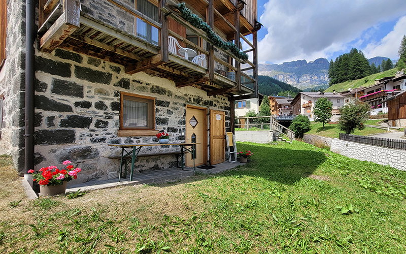 Außenansicht des Chalet Royal in Arabba, mit Steinfassade, Holzbalkonen und einer grünen Wiese.