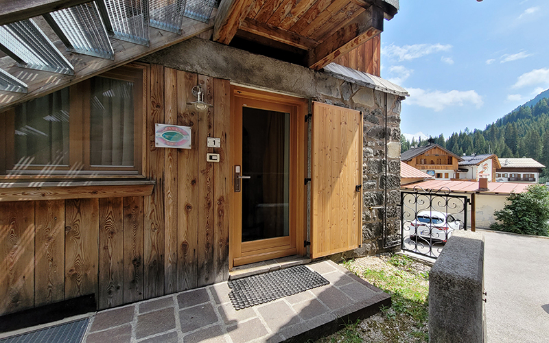 Eingang der Erdgeschosswohnung im Chalet Royal in Arabba, mit Holztür und Fenster.
