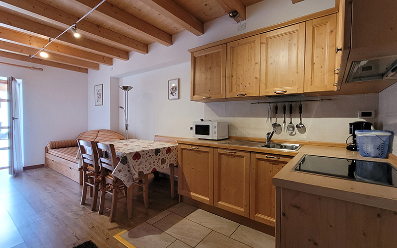 Ausgestattete Küche und heller Essbereich aus Holz, mit Tisch und Bank, in einer Wohnung des Chalet Royal.