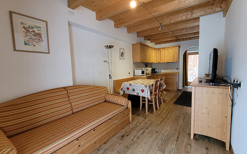 Geräumiges Wohnzimmer mit Schlafsofa und ausgestatteter Küche in einem Apartment des Chalet Royal in Arabba.