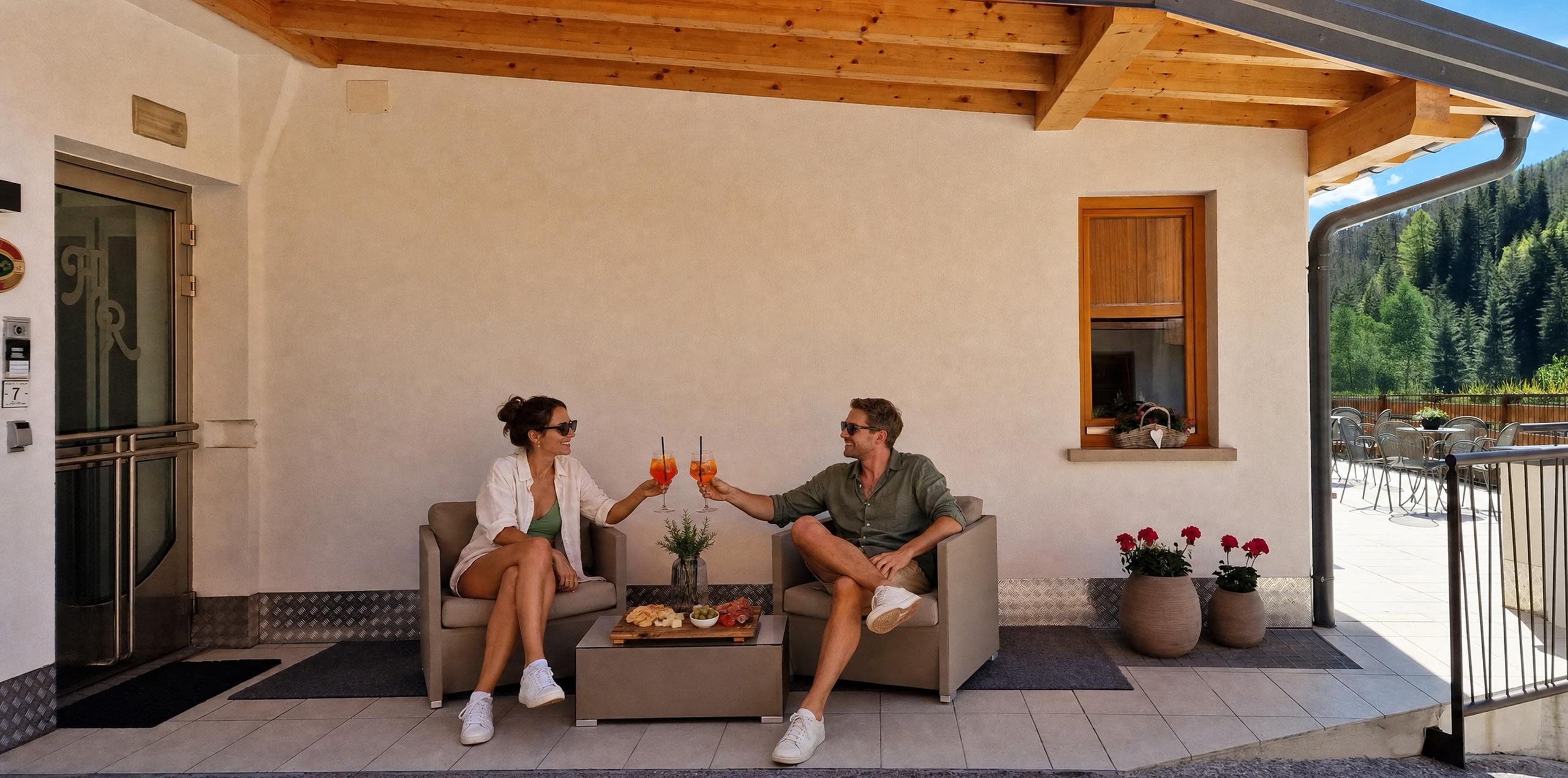 Lächelndes Paar genießt einen Aperitif auf der Terrasse des Garni Royal in Arabba, mit Blick auf die Dolomiten.