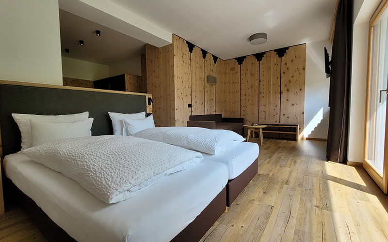 Doppelzimmer im Garni Royal in Arabba mit getrennten Betten, Holzboden und Zirbenholzwand.