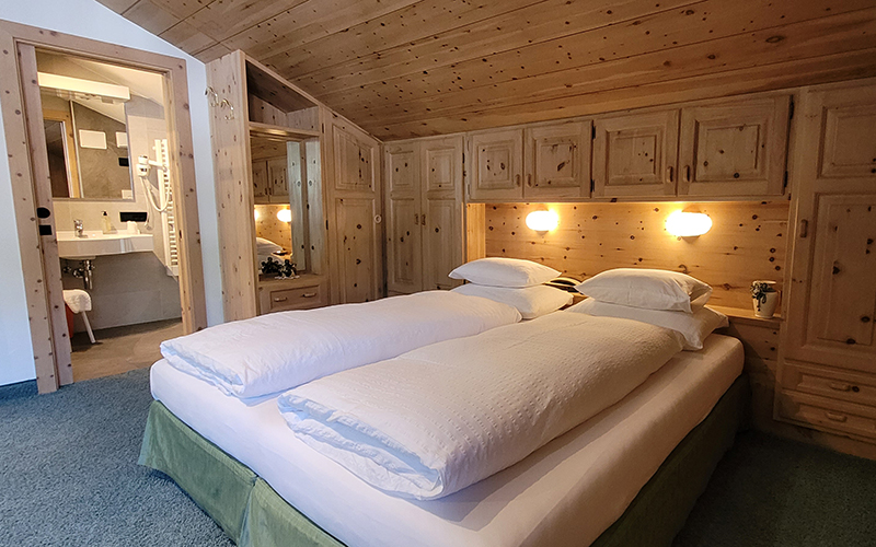 Doppelzimmer aus Zirbenholz im Garni Royal in Arabba, mit eigenem Bad und typischen Dolomiten-Möbeln.