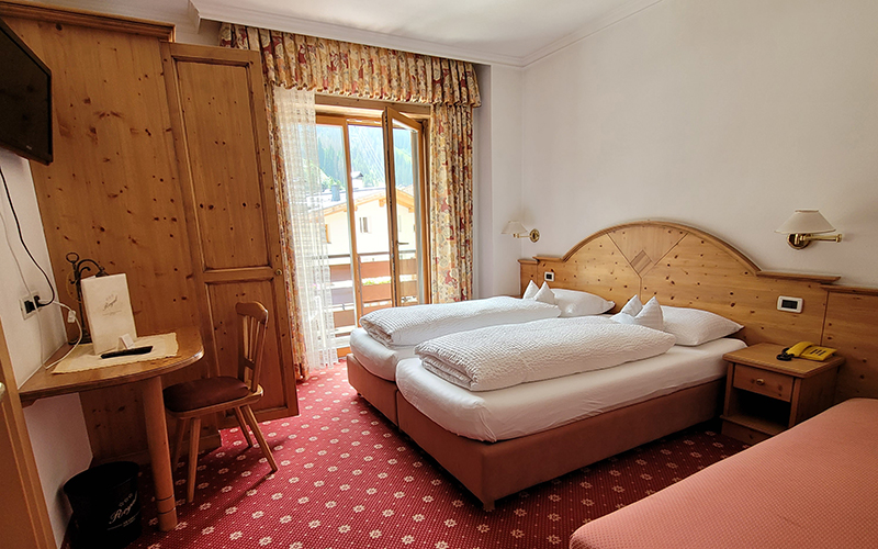 Heller Essbereich aus Holz mit Bank und Stühlen, Tisch mit karierter Tischdecke und Blick auf die Dolomiten.