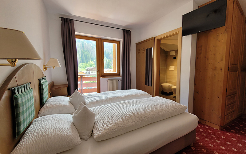 Appartement Alpenroyal in Arabba: Wohnzimmer mit Schlafsofa, Esstisch und Blick auf die Dolomiten.