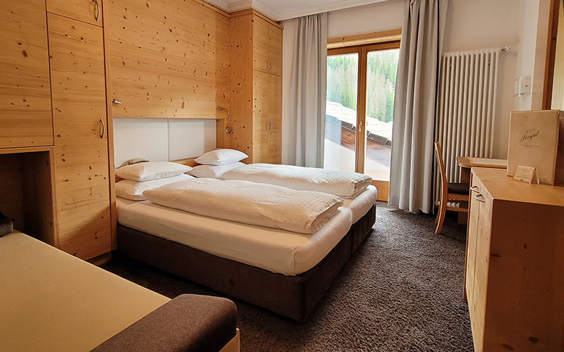 Doppelzimmer aus Zirbenholz im Garni Royal in Arabba, mit Zustellbett, Balkon und Dolomitenblick.