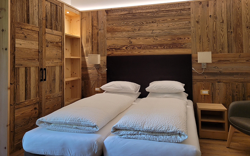 Doppel- oder Zweibettzimmer im Garni Royal in Arabba, mit Zirbenholzmöbeln und Einzelbetten.