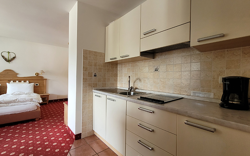 An Alpenroyal apartment in Arabba with a bedroom and equipped kitchenette, ideal for a holiday in the Dolomites.