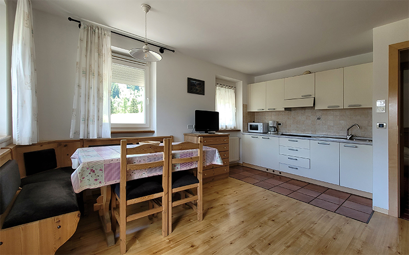 Alpenroyal apartment in Arabba: Equipped kitchen and dining area in mountain style, ideal for families.