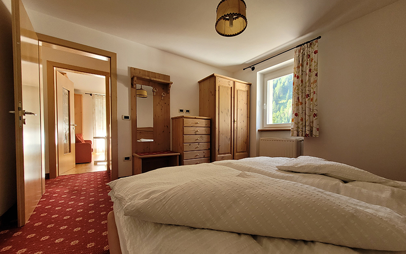 Double bedroom in alpine style at Apartment Alpenroyal, with wooden furnishings and a view of the Dolomites.