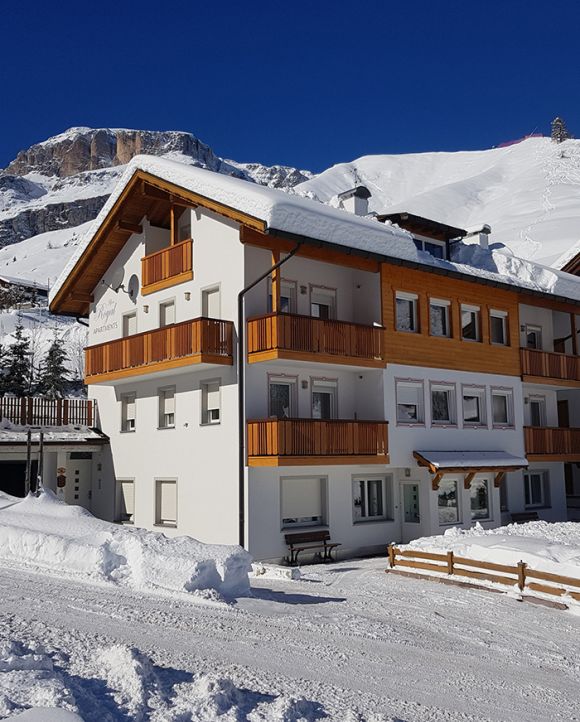 Appartamenti Alpenroyal in Arabba in winter, with fresh snow and the Dolomites in the background.