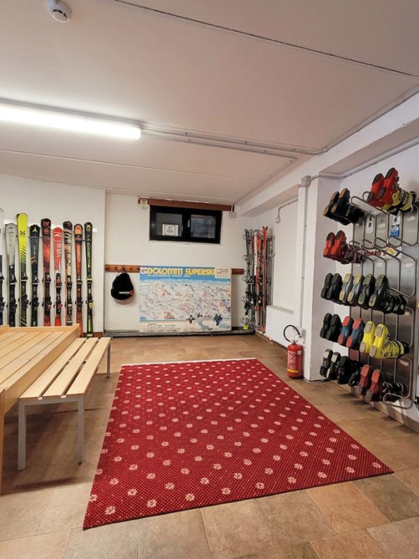 Großer, videoüberwachter Ski- und Skischuhwärmer-Raum des Garni Royal in Arabba, mit Holzbank und rotem Teppich.