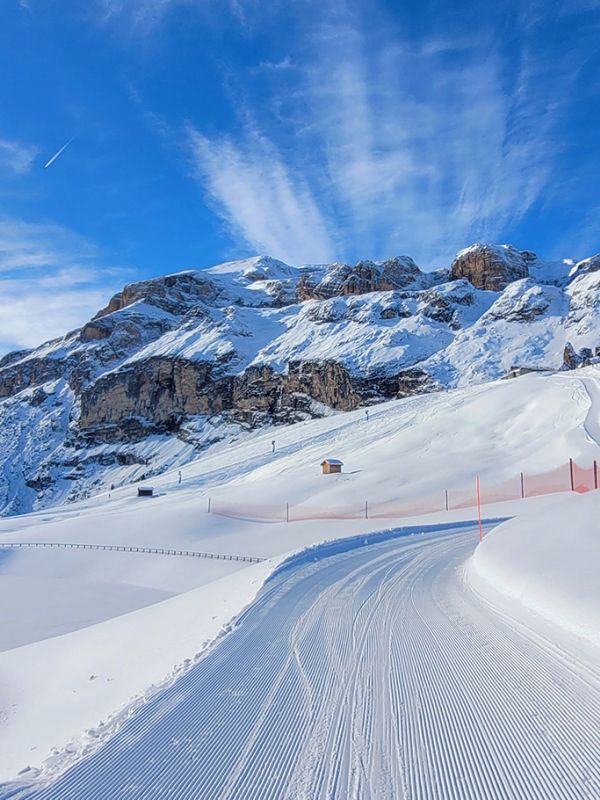 Perfekt präparierte Skipiste in Arabba, mit den majestätischen verschneiten Dolomiten und einem strahlend blauen Himmel.